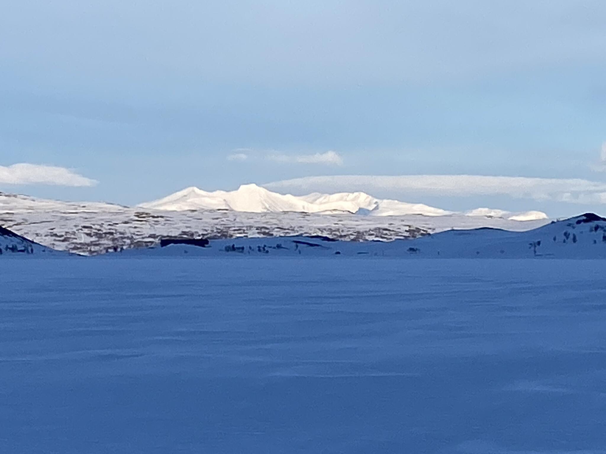 Sylarna i kvällssol och stugan syns nedanför som en stor mörk siluett.