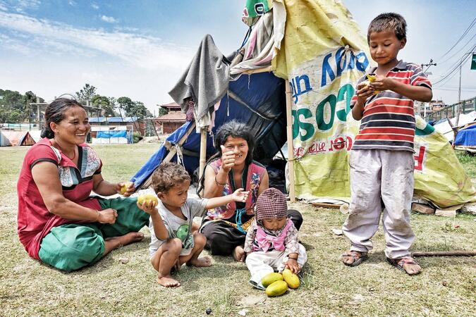 Familj i ett tältläger i Kathmandu får mangos