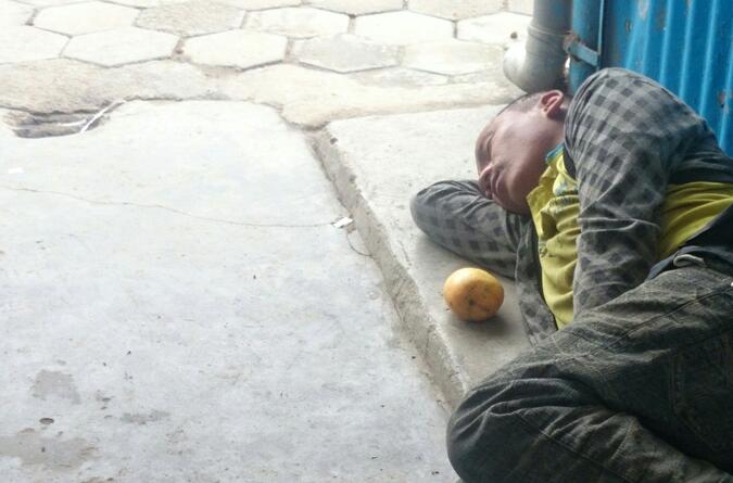 Grabb sover på gatan med en mango, Kathmandu, Nepal