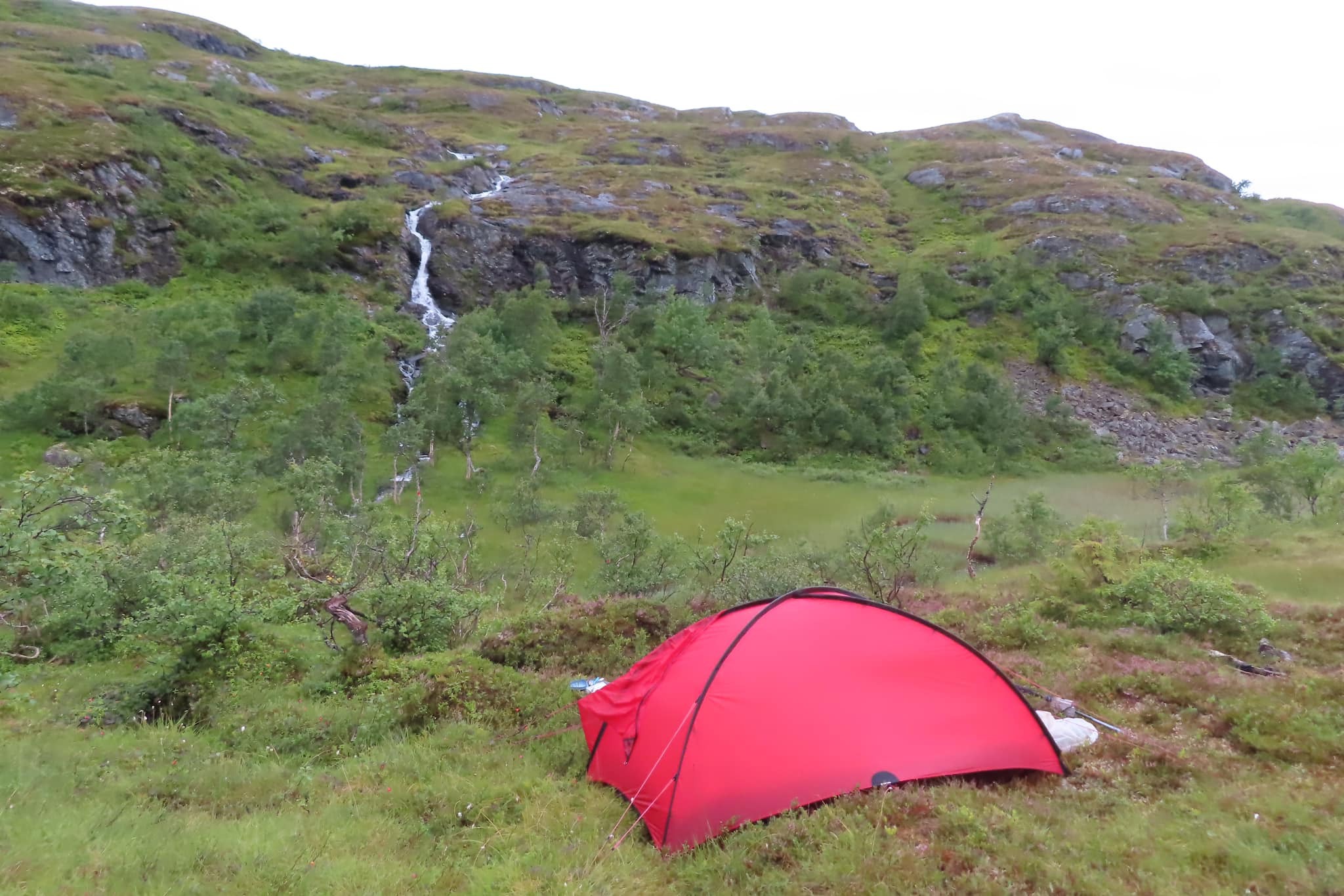 Slog upp tältet mellan regnskurar. 3 augusti. I vattenfallet på andra sidan dalen gick en störtvåg efter en skur. Som att en fördämning brast och flödet mångfaldigades. Jag hörde hur vattenmassorna i störtvågen kom.