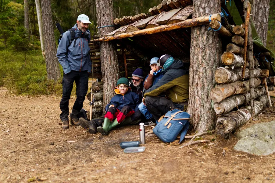 Barn och vuxna vid vid ett vindskydd i skogen