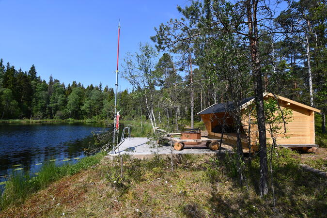 Vindskydd med grillplats och badbrygga vid Svalesjön längs Tremilaleden.