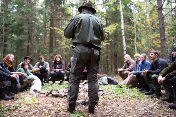 Lars Fält står och talar inför en grupp ute i skogen.