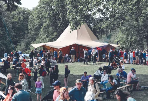 En stor tältkåta med många människor samlade runt